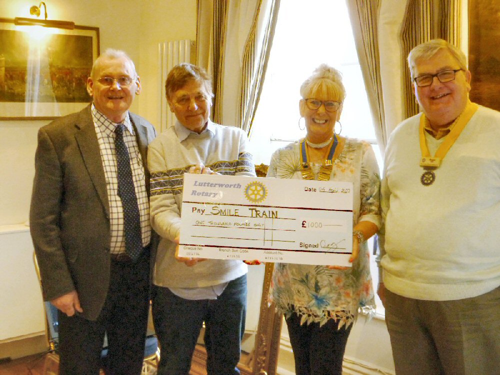 Photograph: Three Rotarians hand giant cheque for £1000 to Smile Train representative, Peter James.